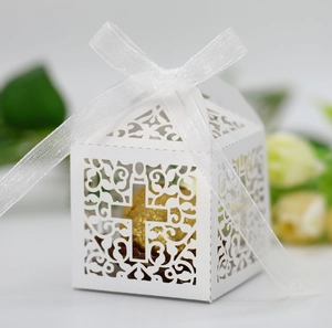Detail of white laser-cut wedding favor box with cross pattern and silk ribbon