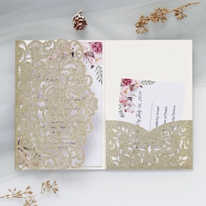 Detail of laser cut gold glitter invitation with elegant floral cards and envelopes