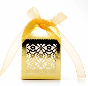 Elegant hollow floral gold wedding favor box with a satin ribbon on white background