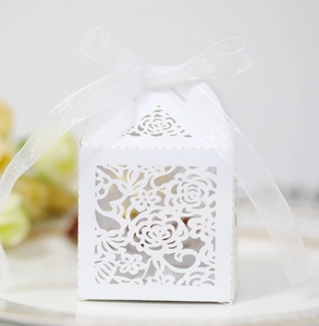 Macro shot of white laser-cut hollow rose patterns on a wedding candy gift box