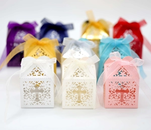 Laser-cut wedding favor boxes with cross motifs and ribbons in multiple colors