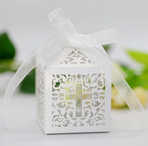 Detailed laser-cut white wedding favor box featuring a cross pattern and a sheer ribbon