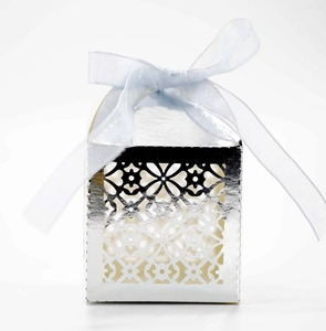 Detail of silver laser-cut hollow candy box with floral patterns and blue silk ribbon bow
