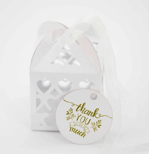 Close-up of white laser-cut wedding favor box with heart pattern and thank you tag