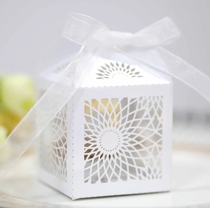 Macro detail of laser-cut sunflower pattern on white gift box with silk ribbon bow