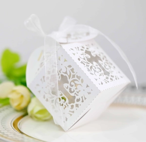 Elegant white laser-cut wedding favor box with floral patterns and a satin ribbon bow