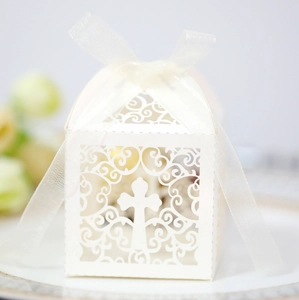 Close-up of laser-cut white favor box with cross design and white organza ribbon bow