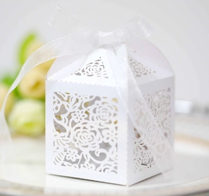 Detailed laser-cut rose patterns on a white wedding favor box with an organza ribbon
