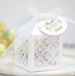 Macro shot of white laser-cut floral wedding candy box with thank you tag and ribbon