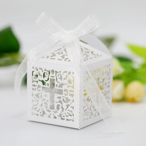 Detailed laser-cut white wedding favor box featuring cross and vine patterns with ribbon