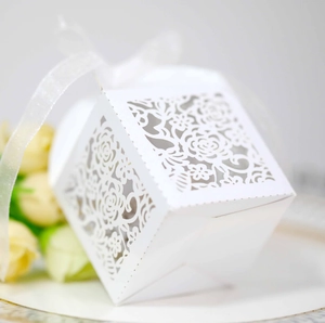 Detailed laser-cut rose pattern on white wedding favor box with a translucent ribbon bow