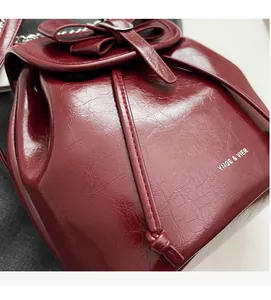 Detail of burgundy leather bucket bag with bow decoration and metal chain strap