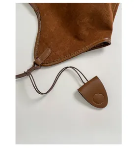 Macro shot of dark brown suede tote bag featuring a leather pendant and fine stitching