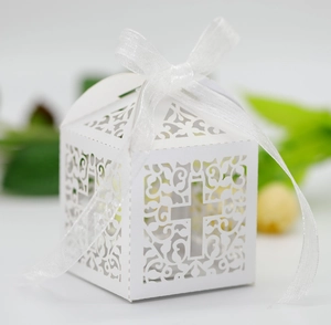 Detailed laser-cut wedding favor box with white cross pattern and organza ribbon