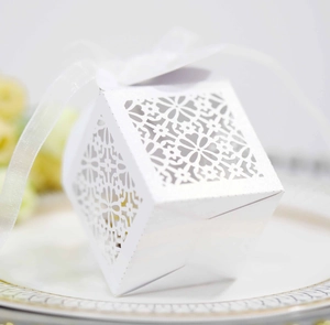 Detailed laser-cut floral patterns on a white wedding favor box with a soft ribbon bow