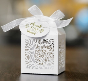 Macro view of white laser-cut rose gift box with pearlescent finish and thank you tag