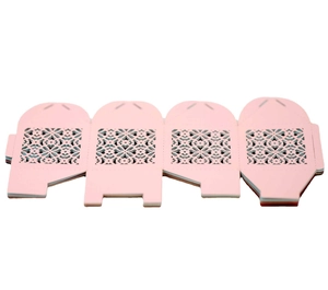 Flat lay of pink laser-cut paper favor boxes with intricate floral and heart patterns
