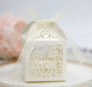 Detail of laser-cut cross gift box in pearlescent white paper with a chiffon ribbon tie