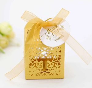 Detailed laser-cut pattern on gold candy box with silk ribbon and thank you tag