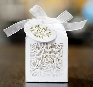 Detail of white laser-cut rose wedding favor box with silk ribbon and thank you tag