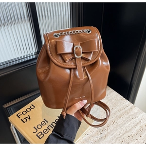Detail of brown vintage backpack featuring bow decoration and silver metal chain