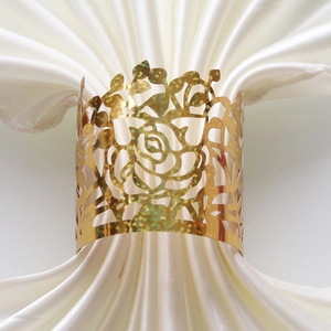 Detailed view of a laser-cut gold rose napkin ring on a white silk pleated napkin