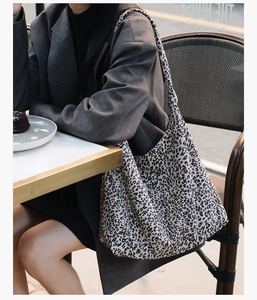 Gros plan du sac cabas léopard associé à un blazer gris dans un café en plein air