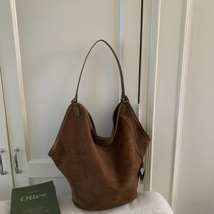 Close-up of deep brown suede tote bag with leather tag hanging on a side strap