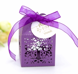 Detail of purple hollow wedding favor box with laser-cut floral pattern and thank you tag