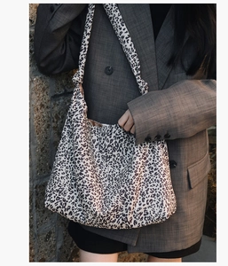 Gros plan d'un sac cabas imprimé léopard associé à un blazer gris pour un look chic