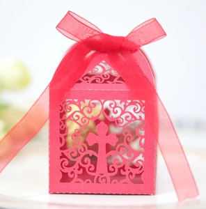 Detail of red laser-cut wedding favor box with cross design and organza ribbon bow
