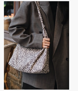 Détail d'un sac cabas en toile à imprimé léopard porté avec un blazer gris chic