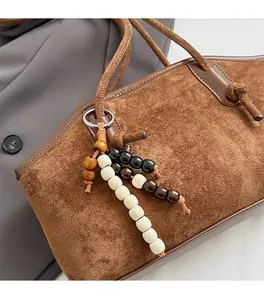 Detail der braunen Wildleder-Tragetasche mit Retro-Perlen-Quasten auf grauem Anzug