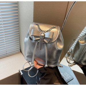 Close-up of metallic silver mini backpack with ribbon bow and elegant chain detail