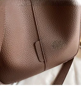 Close-up of brown pebbled leather texture and precision stitching on stylish bucket bag