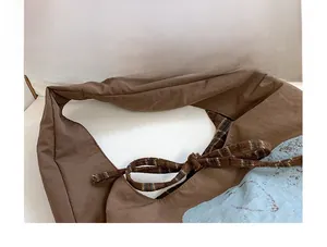 Detailed macro view of the brown canvas tote bag with blue abstract print and plaid strap