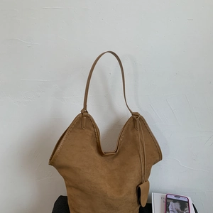 Detail of a large brown suede tote bag with a unique V-shaped rim and shoulder strap
