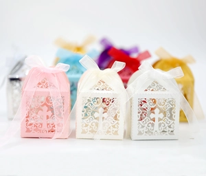 Detail of laser-cut hollow cross favor boxes with satin ribbons in multiple colors