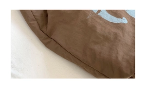Close-up of brown tote bag fabric texture with light blue artistic pattern prints