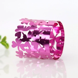 Dettaglio del portatovagliolo in metallo rosa con design a farfalla e fiori traforati