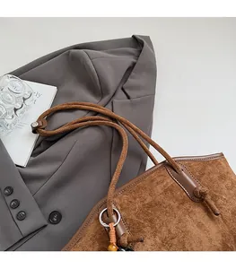 Makroansicht der braunen Wildleder-Tragetasche mit dicken Seilgurten und Silberdetails