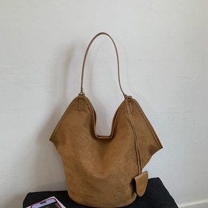 Detail view of brown suede tote bag featuring distinctive winged silhouette and slim straps