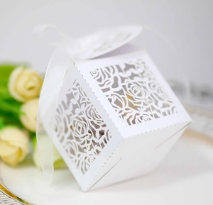 Detail of white laser-cut gift box with floral patterns and satin ribbon for weddings