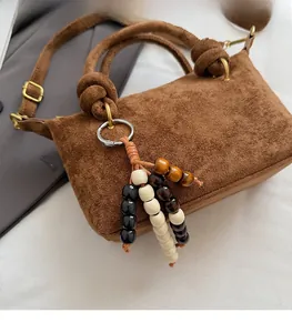 Dettaglio borsa a mano in pelle scamosciata marrone con nappe di legno e fibbia vintage