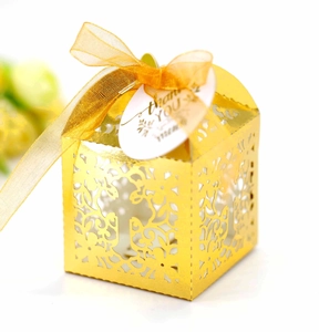 Macro shot of gold hollow laser-cut wedding favor box with ribbon and Thank You tag
