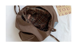 Detail view of large tote bag showing vintage plaid lining and interior leather pocket