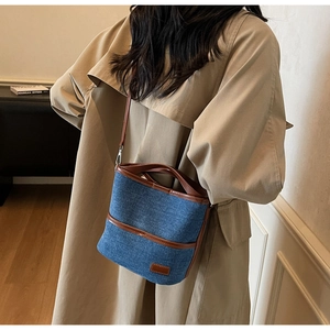 Detail of a vintage denim bucket bag with brown leather trim and adjustable shoulder strap