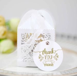 Close-up of white laser-cut rose gift box with silk ribbon and gold thank you tag