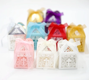 Detailed laser cut favor boxes with cross pattern and silk ribbons in various colors