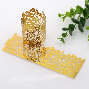 Detail of laser-cut gold glitter cupcake wrapper with elegant rose flower pattern